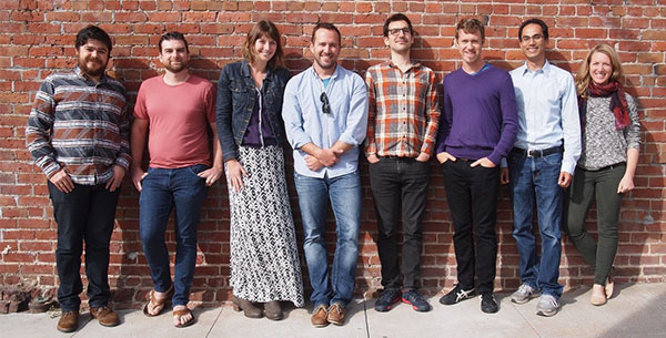 8 members of the Knit Health team standing in front of brick wall